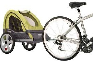 Bicycle with a green and gray kid's trailer attached on a white background.