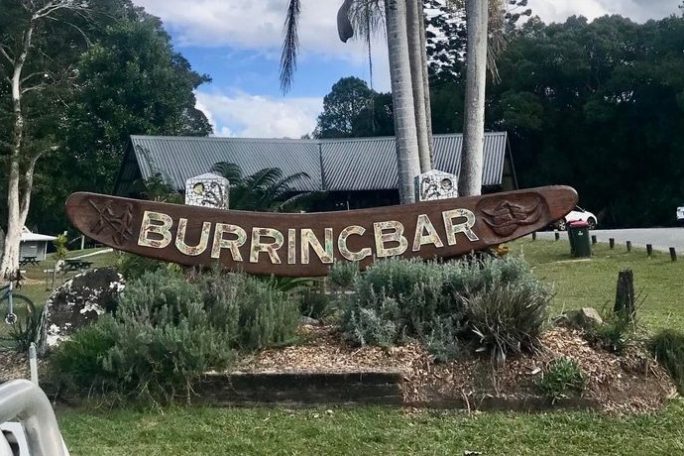 Burringbar sign with palm trees and a building in the background under a cloudy sky.