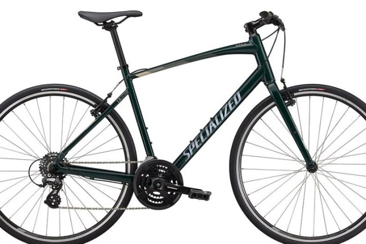 Dark green road bike with drop handlebars and thin tires on a white background.