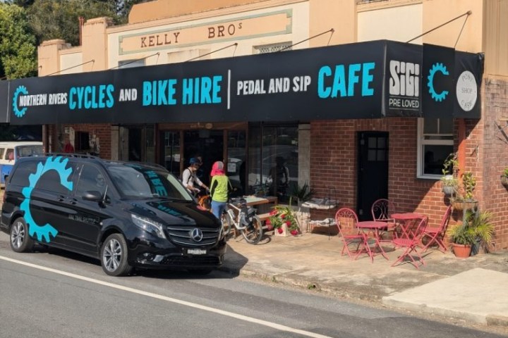 Bike hire and cafe shopfront with van, tables, and customers outside.