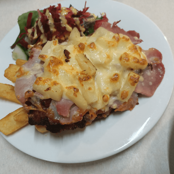 Plate with pizza slice topped with pineapple and cheese, fries, and salad.