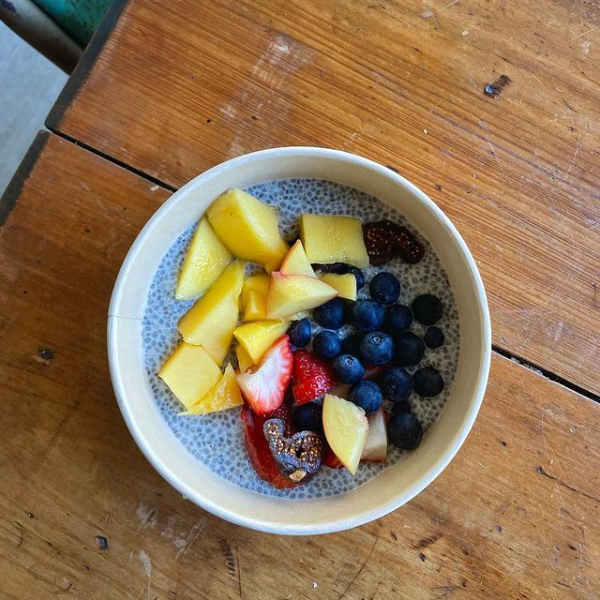 Chia pudding with mango, blueberries, strawberries, and figs in a bowl on a wooden table.