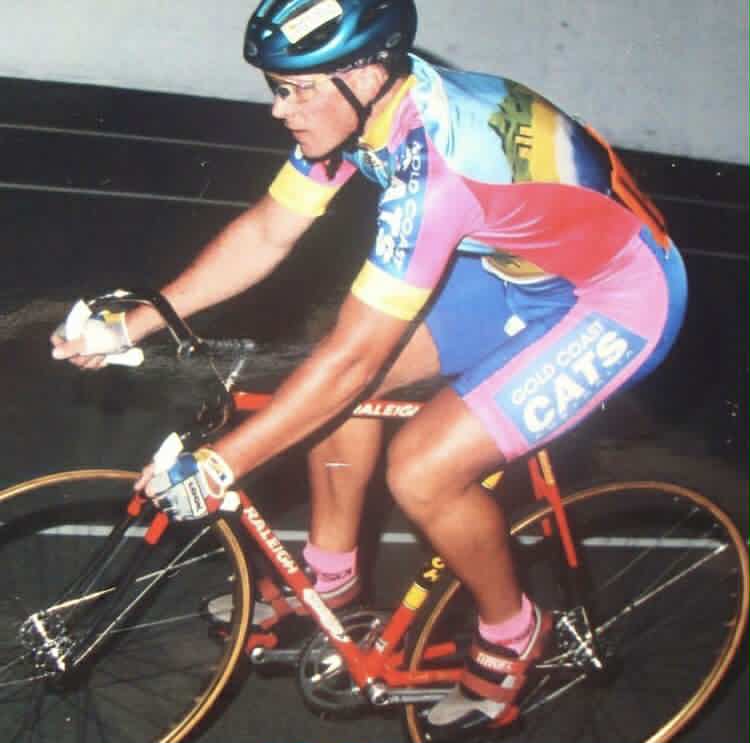 Cyclist in colorful kit riding a racing bike indoors.