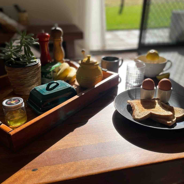 A breakfast scene with toast, boiled eggs, and a tray of condiments in morning sunlight.