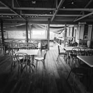 Empty rustic cafe with wooden floors and metal chairs, black and white photo.